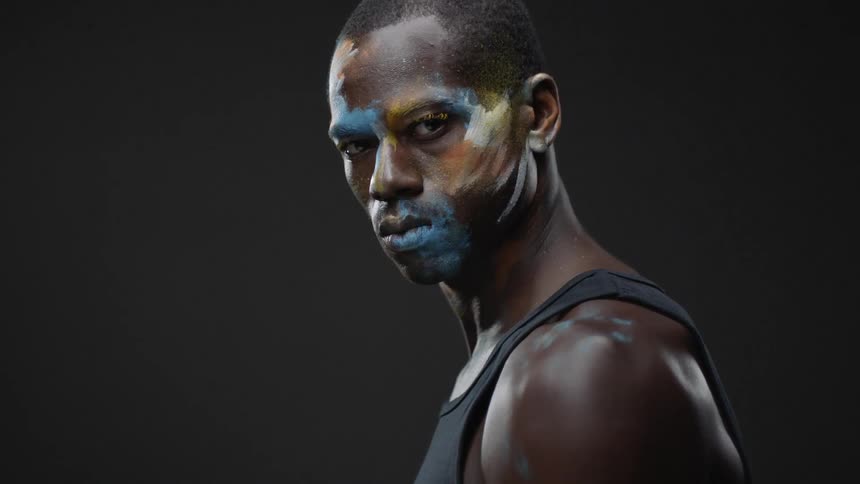 Man looking down turns painted face to look at camera