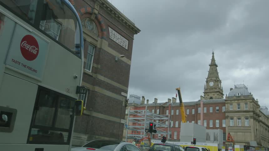 Vehicles are stopped at a red light in a city on a cloudy day