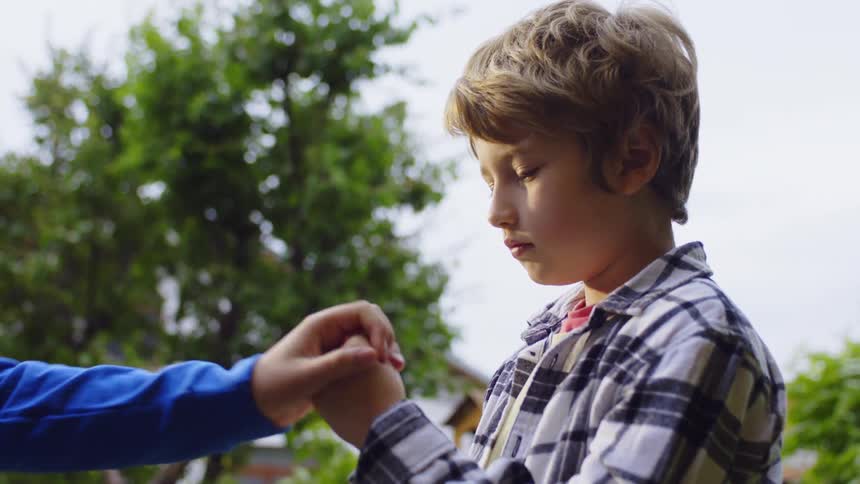 Two male teens play rock paper scissors while standing outside during daytime