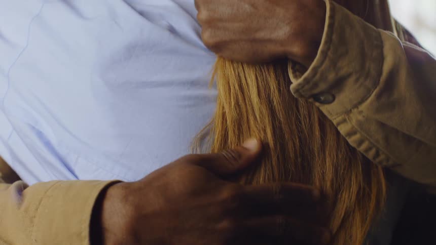 The face of a man who is hugging a woman and stroking her back and touching her orange hair