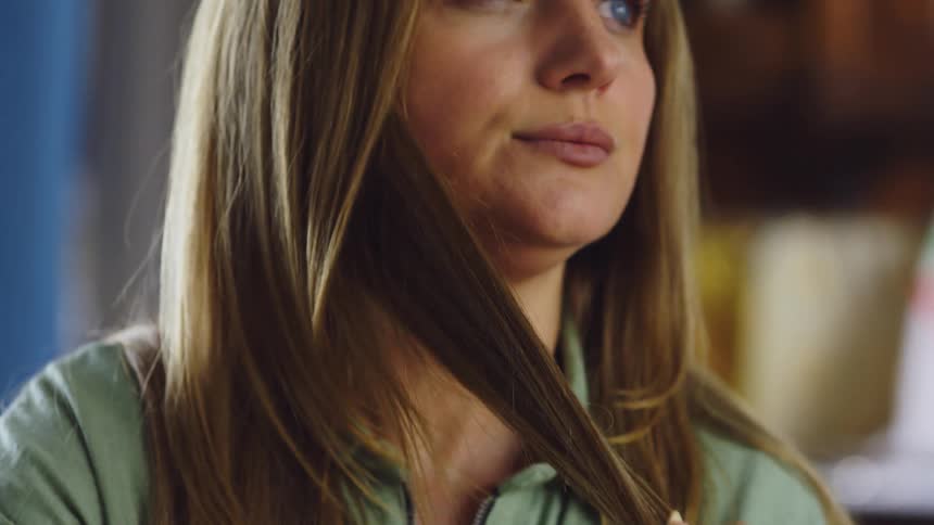 Woman plays with her hair before pulling it across her face and looking downcast
