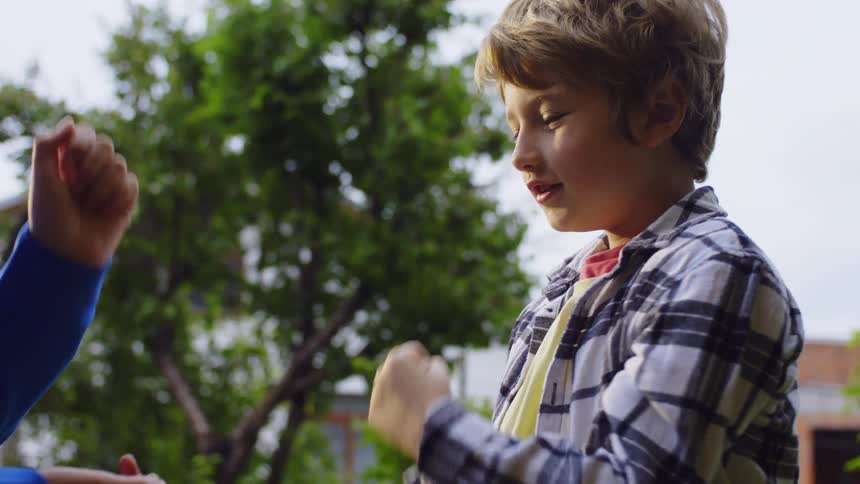 Close up of two male teenagers playing rock paper scissors while standing outdoors during daytime