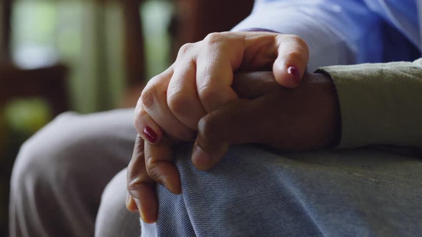 Closeup of two people holding hands in a comforting gesture