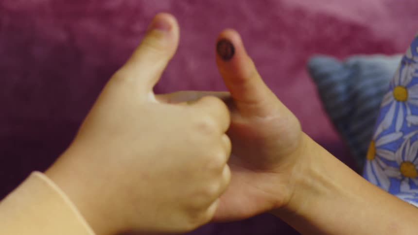 Two children play thumb war locking hands in a playful closeup