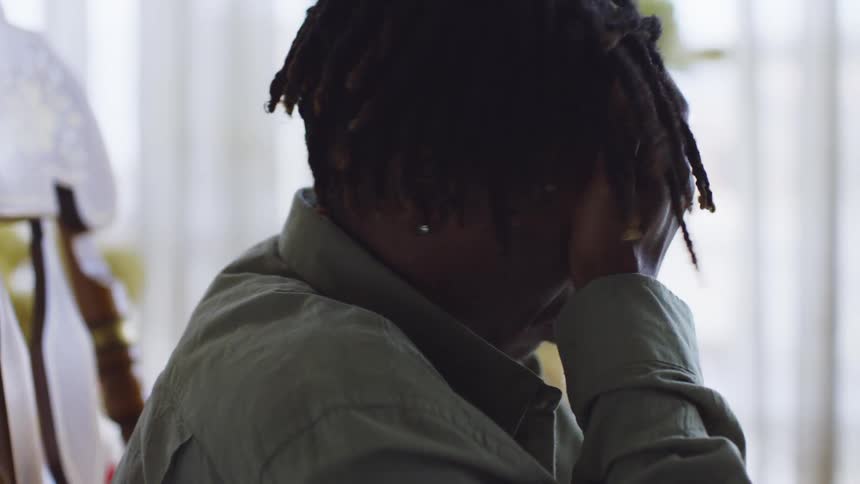 A man sitting at a table worried rubbing his hands and running his hands through his hair nervously