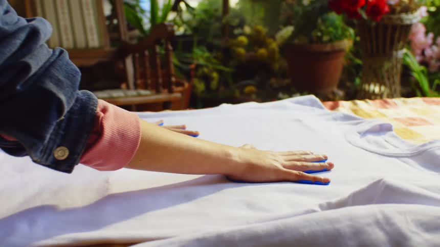 Pair of hands with blue paint being placed on a white shirt