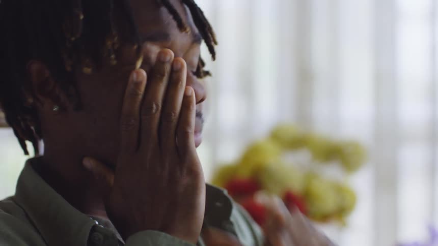A young black man with dreadlocks sitting on a chair lost in deep thought