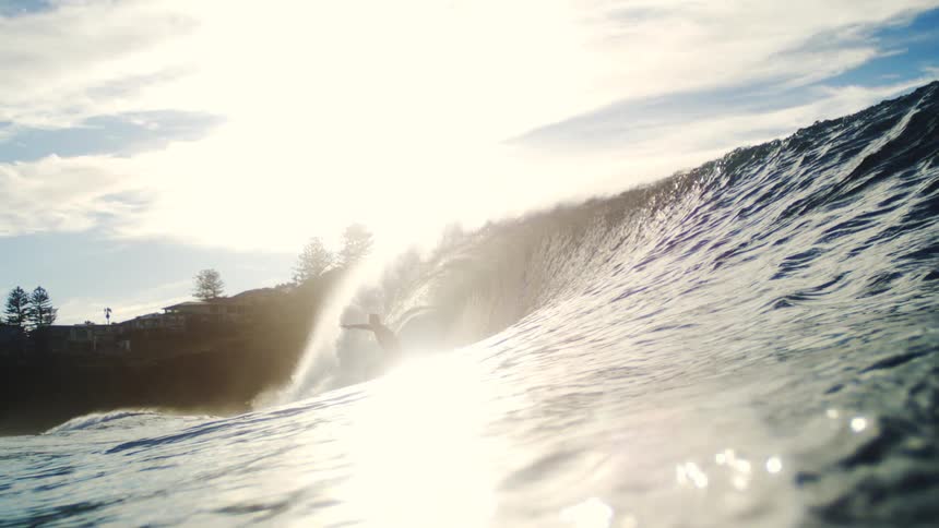 A man is riding the wave near the shore on a sunny day