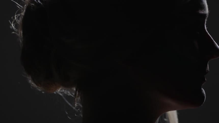 Woman stands in a dark room