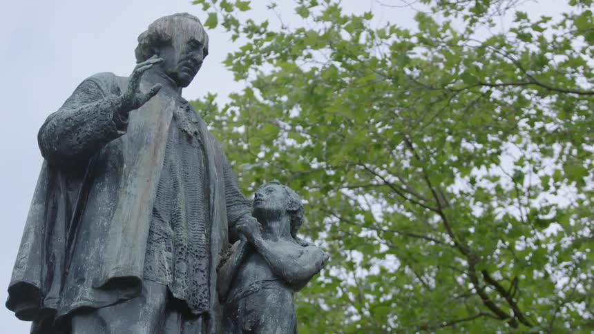 A statue stands tall near a tree