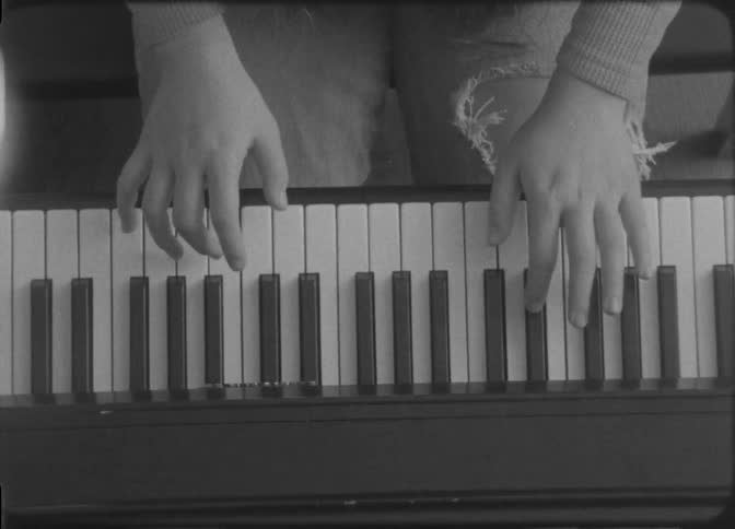 Close up of a womans hands as she plays the keyboard while sitting in a room