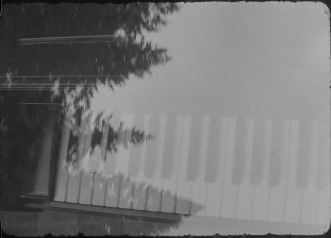 Multiple exposure of a piano contrasted with the silhouette of trees