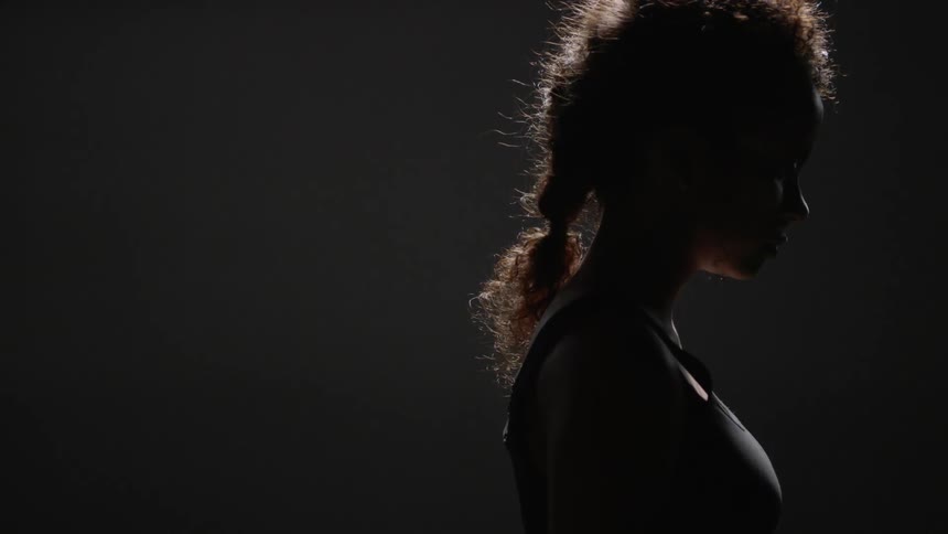 A backlit woman looks up