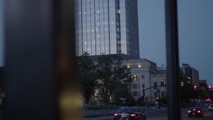 Traffic flows past a skyscraper at dusk