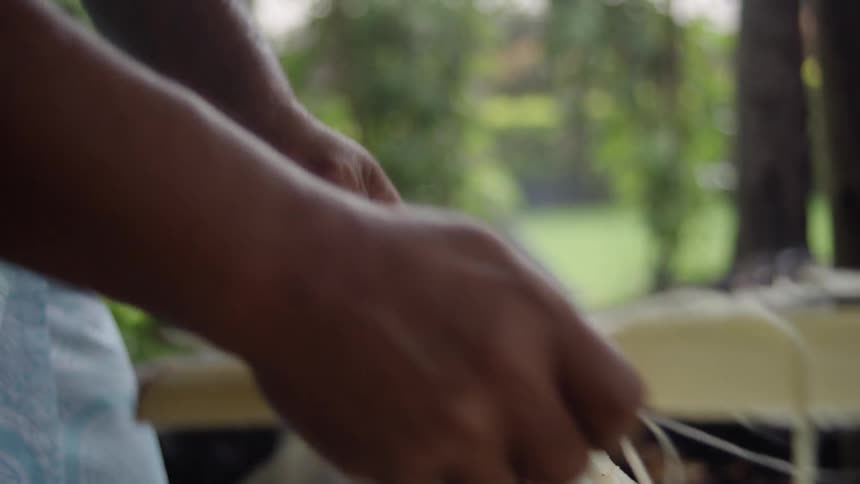 Closeup of hands peeling and shredding palm heart fibers outdoors in a tropical setting
