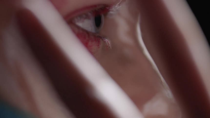 A woman removes her hand from in front of her eyes