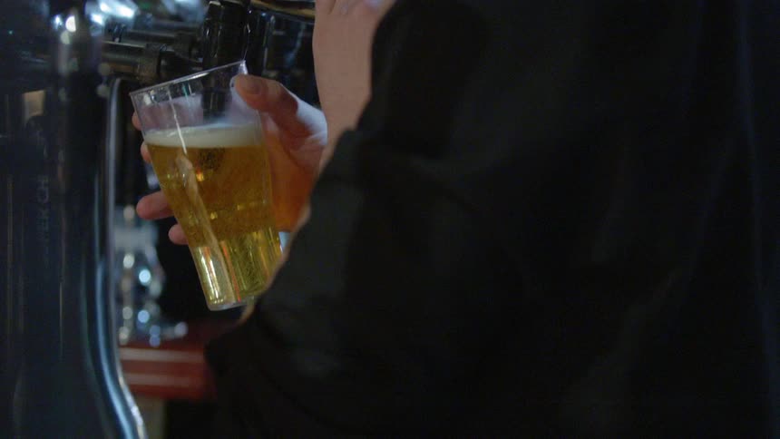 Bartender filling glass cup with beer and handing to customer