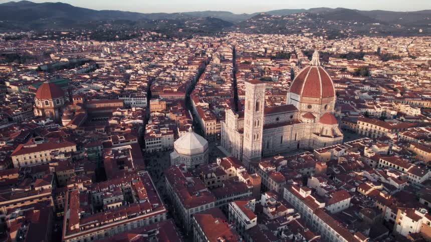 Cathedral towers over low rise buildings in a town containing many red roofed buildings