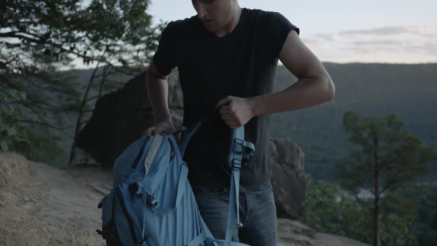 A man removes his backpack and sets it on the ground