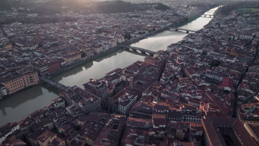 An aerial view of a residential area with many redroofed houses and next to a canal with some bridges passing over it