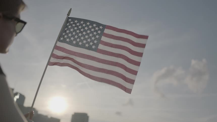 A boy in sunglasses holds an american flag