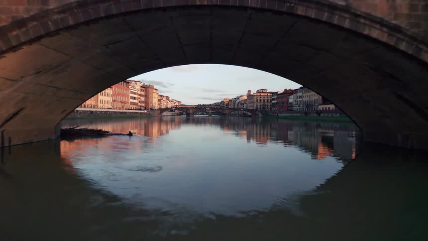 Reflective river water flows under arched bridges connecting residential areas