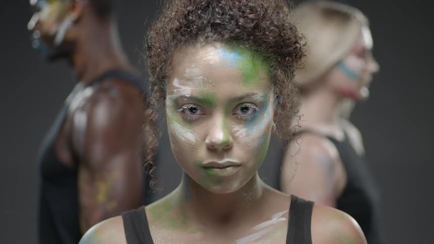 Two women and a man have paint on their faces and bodies