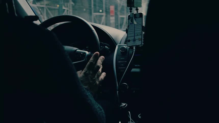 Close up of a male driver driving a car in a city street during daytime