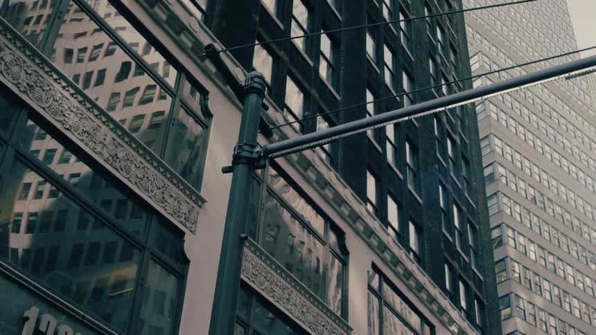 A city view of skyscraper buildings with a streetlight pole visible at midday