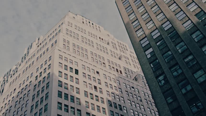 Tall city buildings rise against a cloudy sky