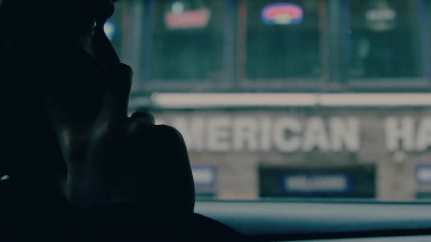 Man sits in a stationary car and talks on his smartphone during the daytime