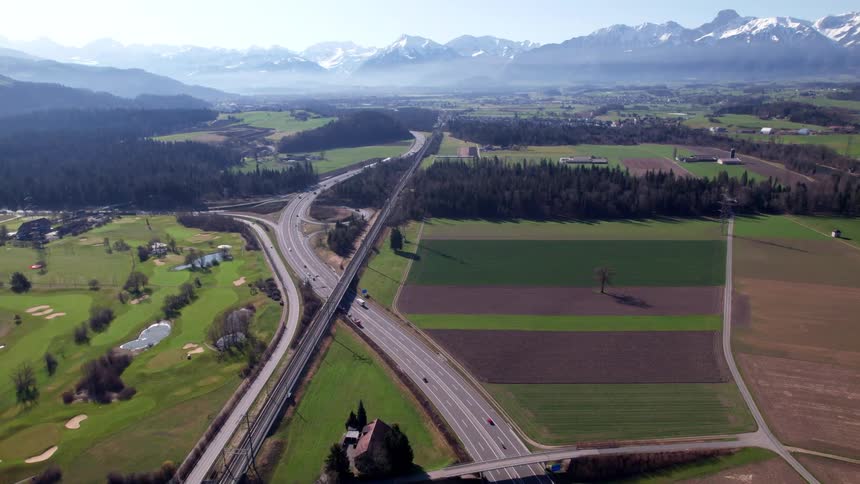 Aerial view of highway and railway cutting through rural fields and mountains