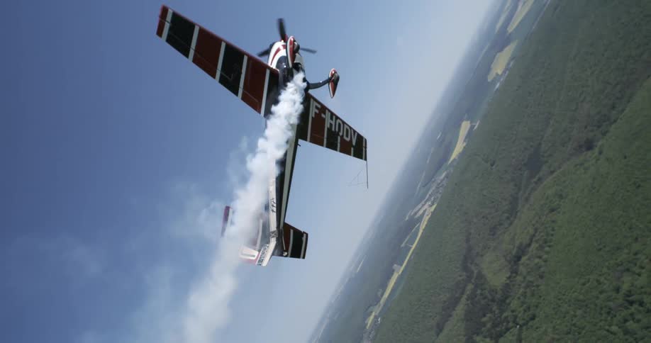 Single engine plane releasing smoke over a wooded area