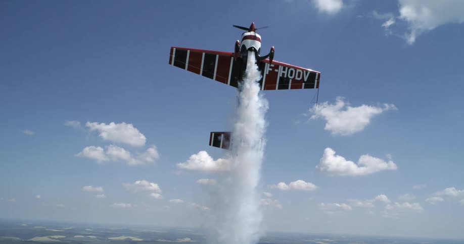 A plane is suspended in midair at midday with thick white smoke ejecting from its engines