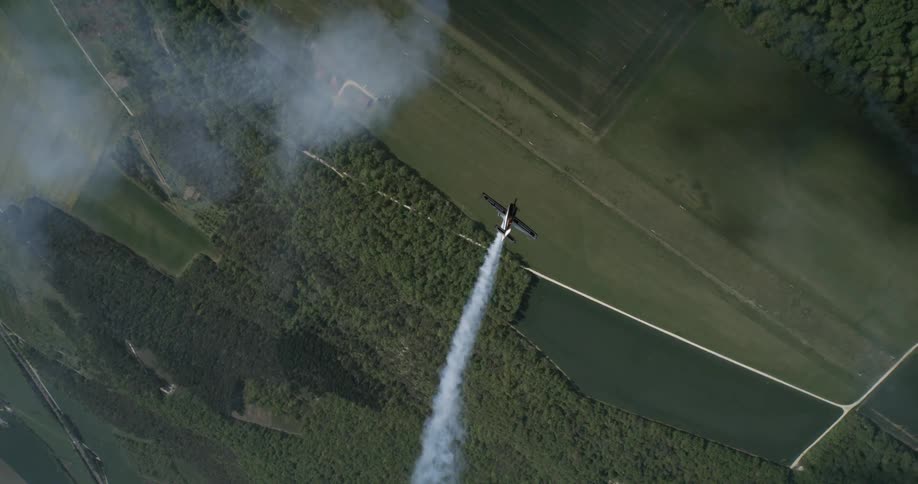 Aerial scene of a small plane releasing smoke and performing aerial maneuvers