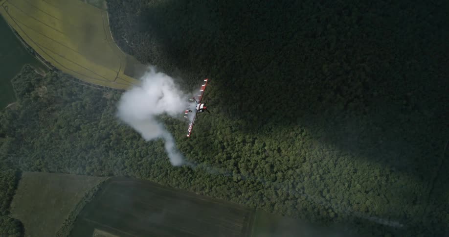 Aerial view of an airplane performing maneuvers and releasing smoke