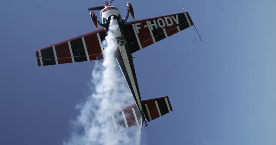 A small single engine plane that is white with blue and red stripes and it is releasing white smoke