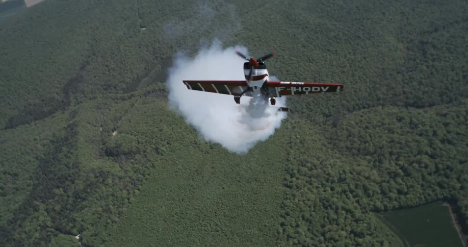Small smoking plane hovers in the air above the rural countryside
