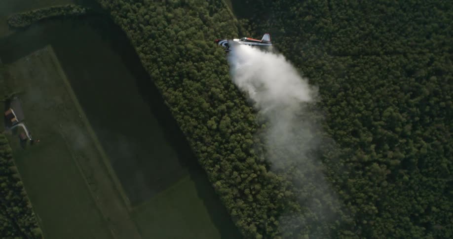 An airplane is flying above a wooded area landscape