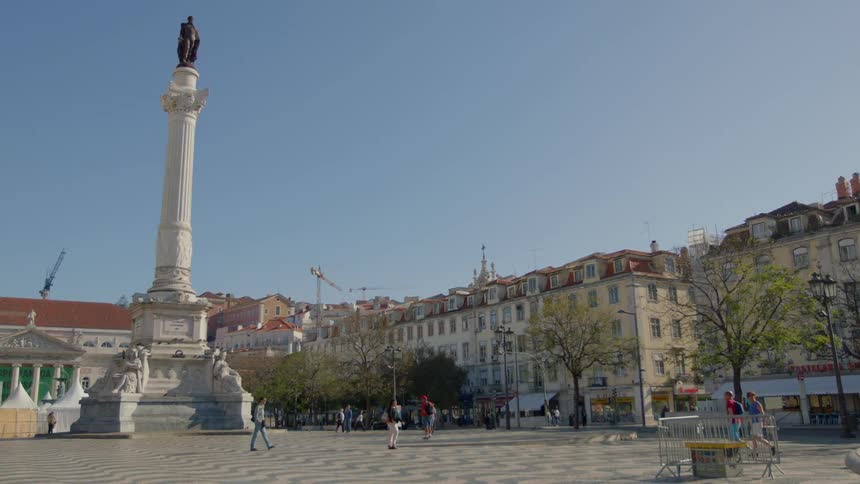 People walk near a statue on a pillar