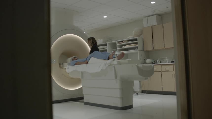 A technician attends a person lying on a table in front of an mri machine