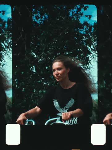 The face of a woman who is riding a bicycle and her hair is moving with the wind