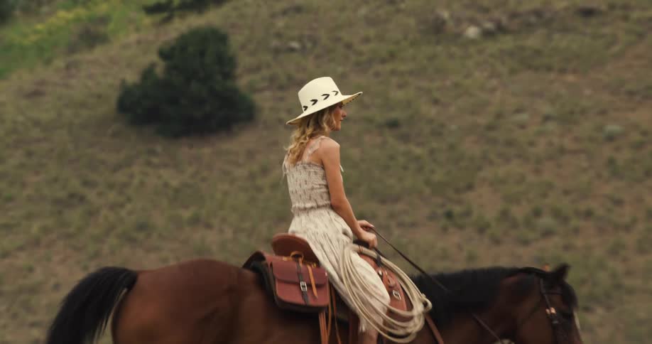 A woman and a man riding horses in a field