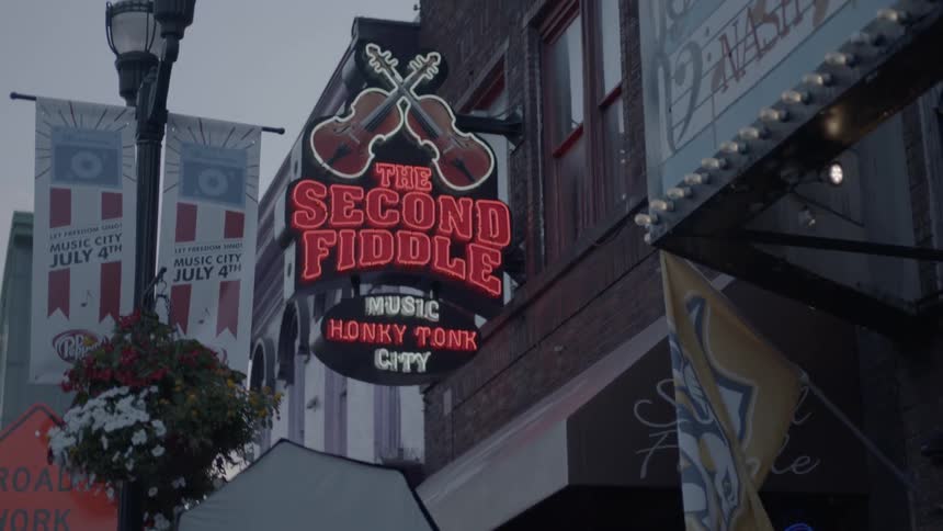 A neon sign hangs above a music venue in a city