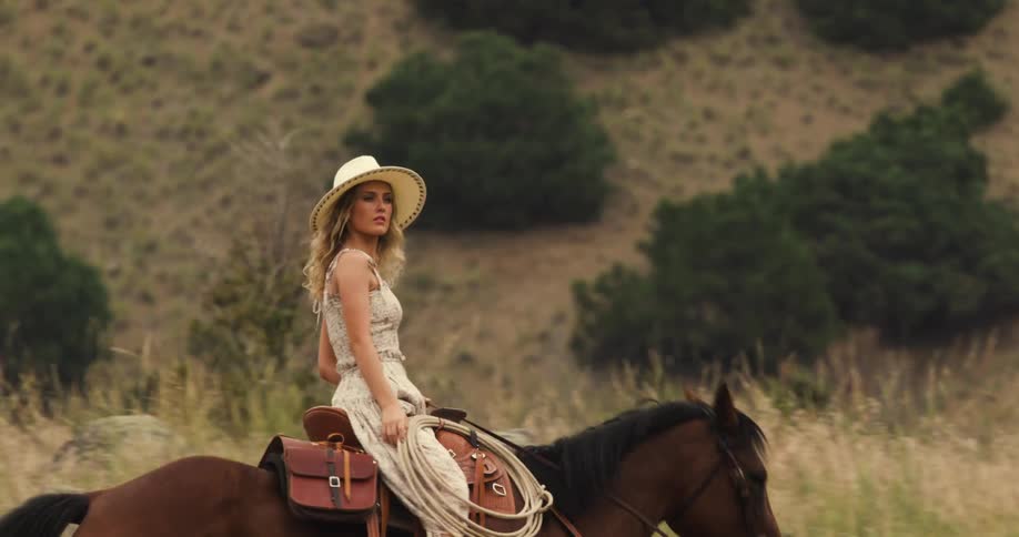 Woman and a man in a hat riding horses through the mountains