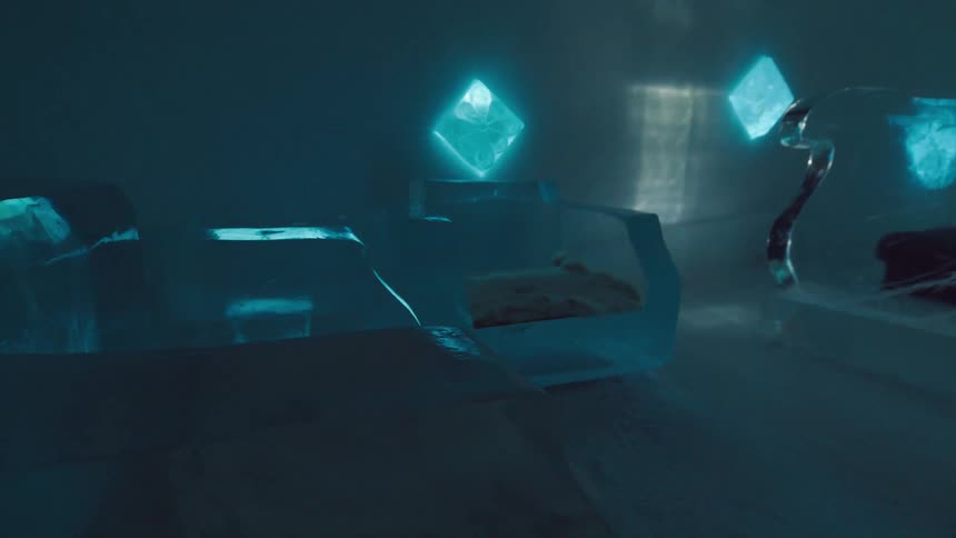 An icy room with glowing blue diamondshaped lights and furniture made entirely of ice