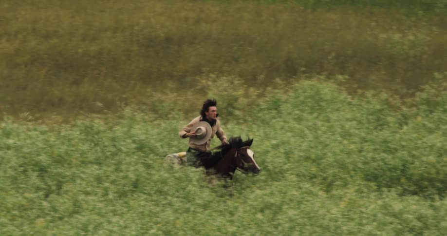 Man with a hat riding a horse in a field with reliefs