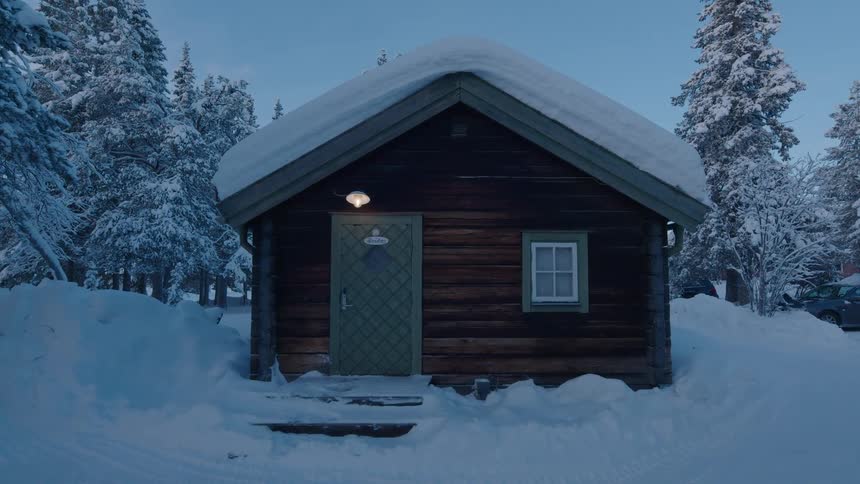 A rustic log cabin with a snowcovered roof sits nestled amongst snowladen pine trees in a wintry landscape at dusk