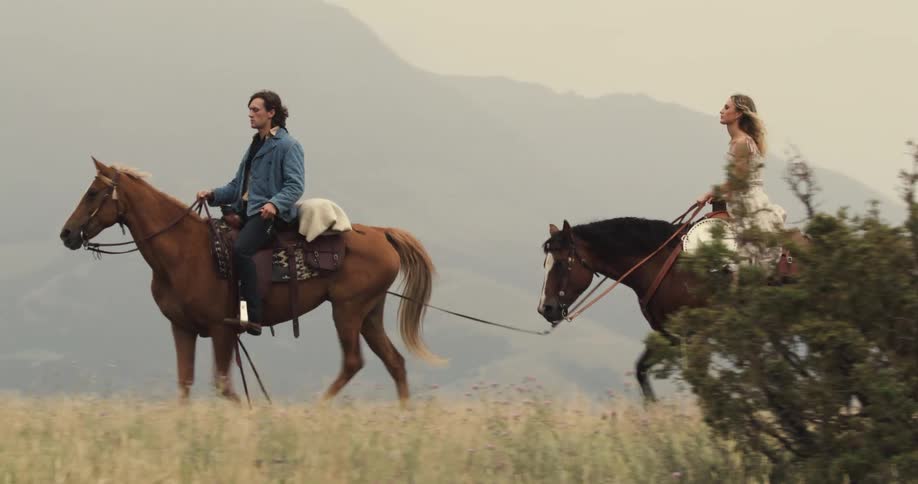 Couple horseback riding on a pasture in the countryside