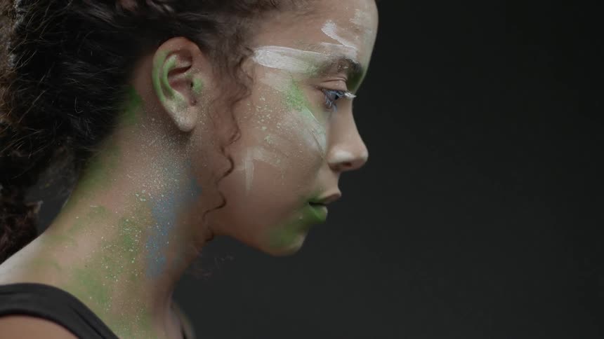A woman's face is covered with colorful paint